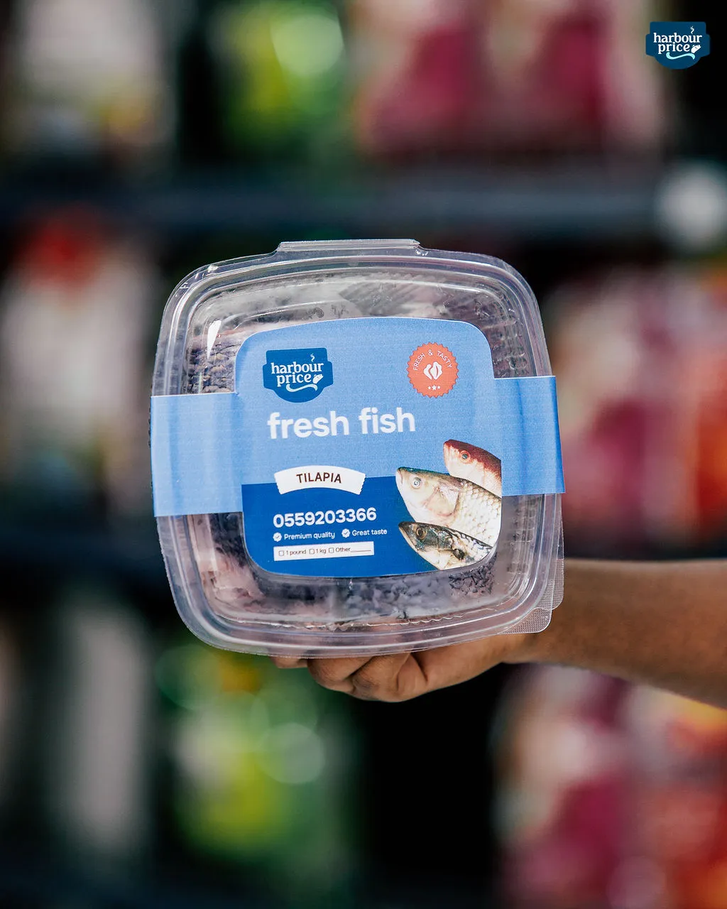 A sealed Harbour Price fresh tilapia pack held up in the freezer aisle